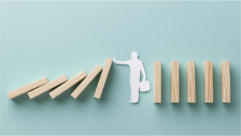 man stopping dominoes from falling